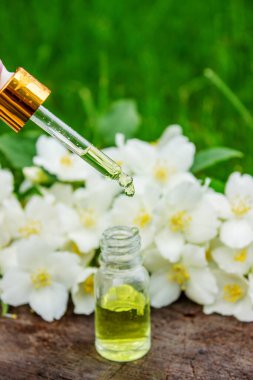 Cam şişede yasemin yağı ve yasemin çiçekleri. Yağlar