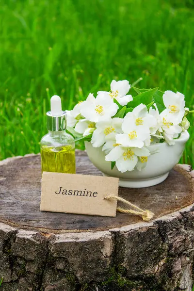 Cam şişede yasemin yağı ve yasemin çiçekleri. Yağlar