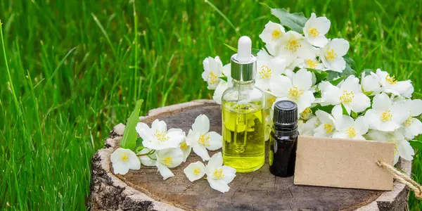 Cam şişede yasemin yağı ve yasemin çiçekleri. Yağlar