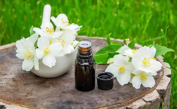 Cam şişede yasemin yağı ve yasemin çiçekleri. Yağlar