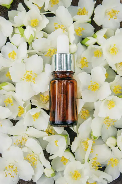 Cam şişede yasemin yağı ve yasemin çiçekleri. Yağlar