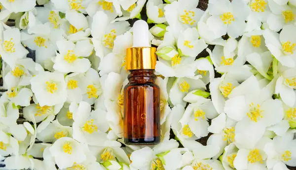 Cam şişede yasemin yağı ve yasemin çiçekleri. Yağlar