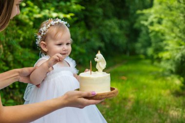 Küçük kızın ilk doğum günü. Annem pasta tutuyor. Kutlama