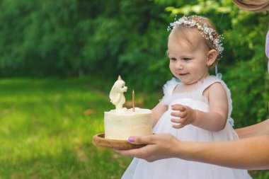 Küçük kızın ilk doğum günü. Annem pasta tutuyor. Kutlama