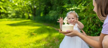 Küçük kızın ilk doğum günü. Annem pasta tutuyor. Kutlama