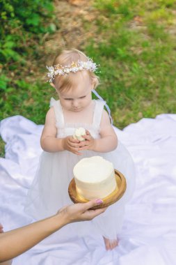 Küçük kızın ilk doğum günü. Annem pasta tutuyor. Kutlama