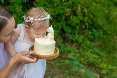 Küçük kızın ilk doğum günü. Annem pasta tutuyor. Kutlama
