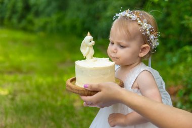 Küçük kızın ilk doğum günü. Annem pasta tutuyor. Kutlama