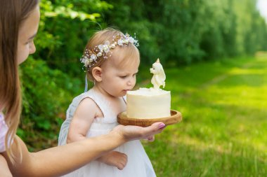 Küçük kızın ilk doğum günü. Annem pasta tutuyor. Kutlama