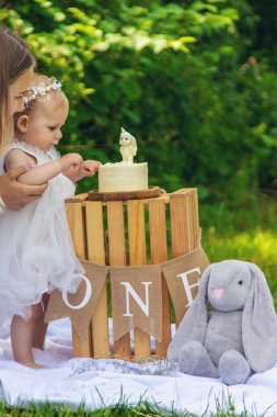 Küçük kızın ilk doğum günü. Annem pasta tutuyor. Kutlama