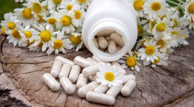 Tahta yüzeyde Papatya Kapsülü ve Taze Papatyalar.