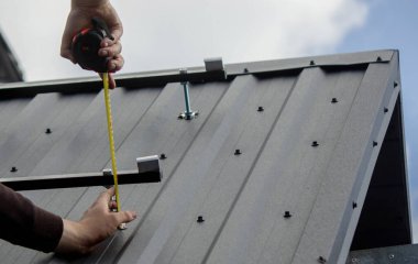 Bir adam çatıya güneş paneli monte ediyor. Seçici odak.