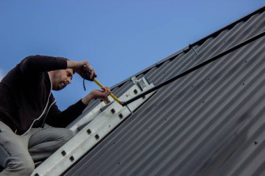 Bir adam çatıya güneş paneli monte ediyor. Seçici odak.