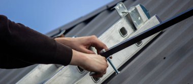 Bir adam çatıya güneş paneli monte ediyor. Seçici odak.