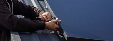 Bir adam çatıya güneş panelleri kuruyor. Seçici odak.