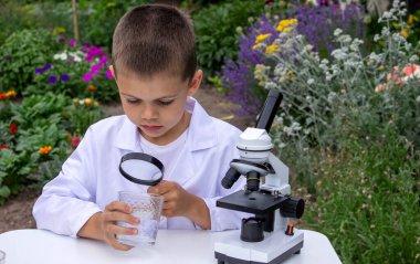 Bir çocuk suyu büyüteçle inceler..