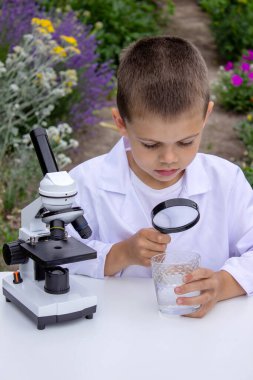 Bir çocuk suyu büyüteçle inceler..