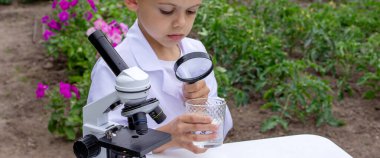 Bir çocuk suyu büyüteçle inceler..