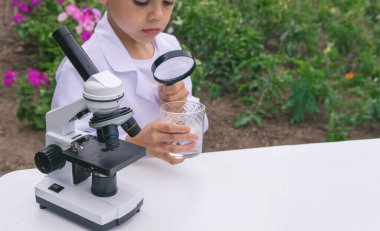 Bir çocuk suyu büyüteçle inceler..