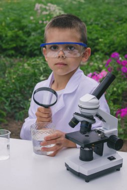 Bir çocuk suyu büyüteçle inceler..