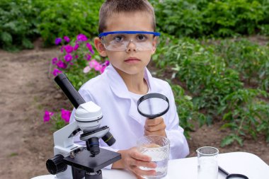 Bir çocuk suyu büyüteçle inceler..