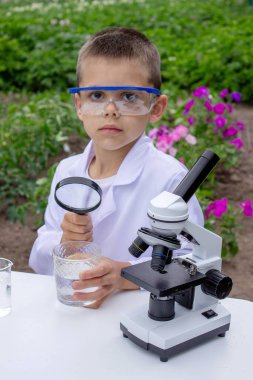 Bir çocuk suyu büyüteçle inceler..