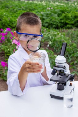 Bir çocuk suyu büyüteçle inceler..