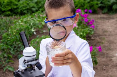 Bir çocuk suyu büyüteçle inceler..