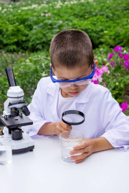 Bir çocuk suyu büyüteçle inceler..