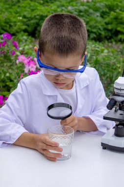 Bir çocuk suyu büyüteçle inceler..