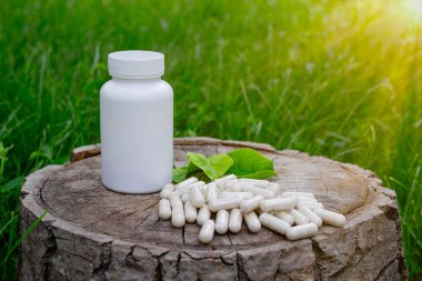 Kapsüllerde bitkisel ilaçlar, ağaç gövdesinde bitki yaprakları.