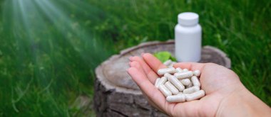 Kapsüllerde bitkisel ilaçlar, ağaç gövdesinde bitki yaprakları.