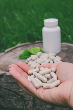 Kapsüllerde bitkisel ilaçlar, ağaç gövdesinde bitki yaprakları.