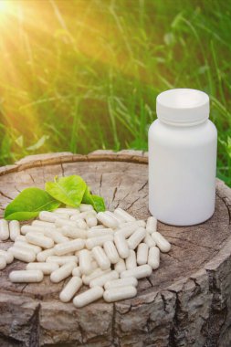 Kapsüllerde bitkisel ilaçlar, ağaç gövdesinde bitki yaprakları.