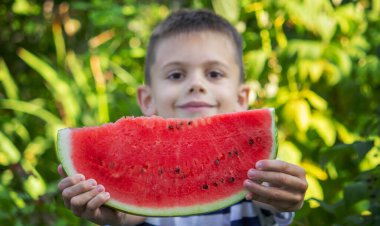 Mutlu çocuk karpuz yiyor. Yaz.