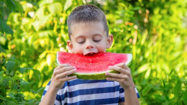 Mutlu çocuk karpuz yiyor. Yaz.