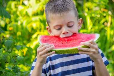Mutlu çocuk karpuz yiyor. Yaz.