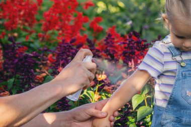 Baba çocuğuna sivrisinek kovucu sıkar.