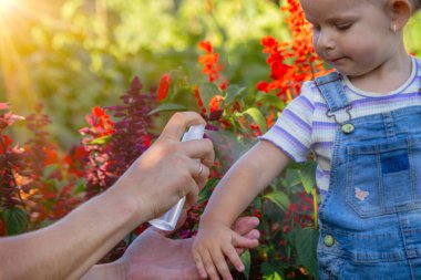 Baba çocuğuna sivrisinek kovucu sıkar.