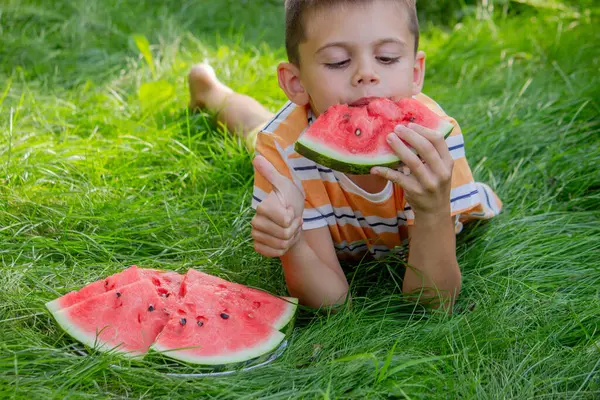 Mutlu çocuk yaz çimenlerinde karpuz yiyor..