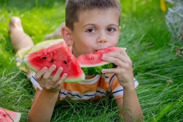 Mutlu çocuk yaz çimenlerinde karpuz yiyor..