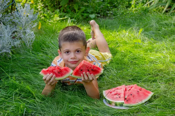 Mutlu çocuk yaz çimenlerinde karpuz yiyor..