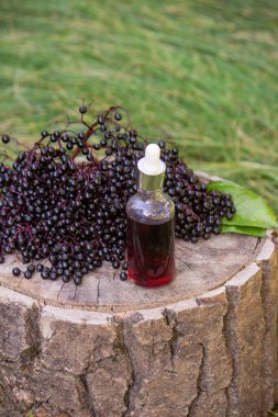 Halk ilaçları ve ahşap bir kütükte doğal siyah mürver şurubu. Mürver çileği..