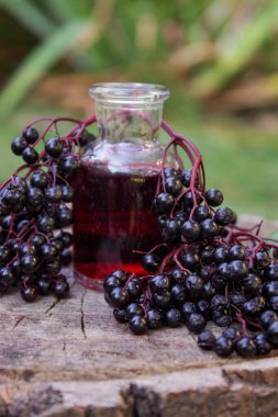 Halk ilaçları ve ahşap bir kütükte doğal siyah mürver şurubu. Mürver çileği..