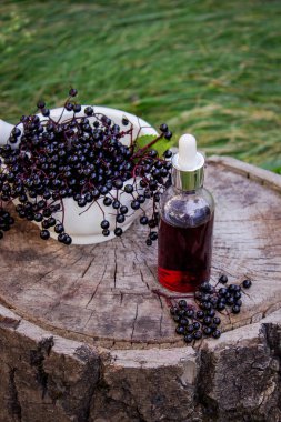 Halk ilaçları ve ahşap bir kütükte doğal siyah mürver şurubu. Mürver çileği..