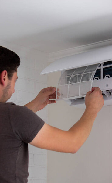 Maintenance Complete. Technician Installing Clean Air Filter in Air Conditioner.