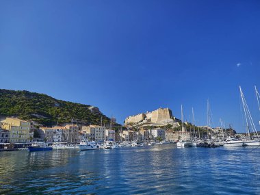 Bonifacio şehri, Fransa 'nın Korsika adasındaki Akdeniz' in turkuaz suyuyla çevrili beyaz bir uçurumun üzerinde uzanıyor.