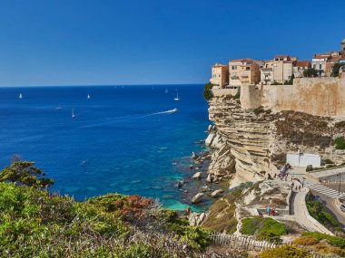 Bonifacio şehri, Fransa 'nın Korsika adasındaki Akdeniz' in turkuaz suyuyla çevrili beyaz bir uçurumun üzerinde uzanıyor.