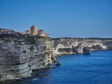Bonifacio şehri, Fransa 'nın Korsika adasındaki Akdeniz' in turkuaz suyuyla çevrili beyaz bir uçurumun üzerinde uzanıyor.