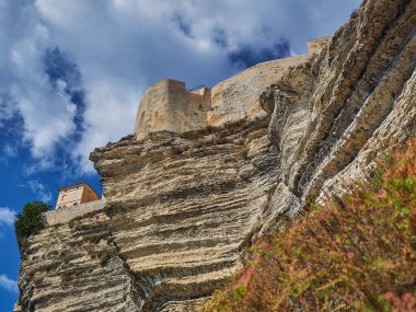 Bonifacio şehri, Fransa 'nın Korsika adasındaki Akdeniz' in turkuaz suyuyla çevrili beyaz bir uçurumun üzerinde uzanıyor.
